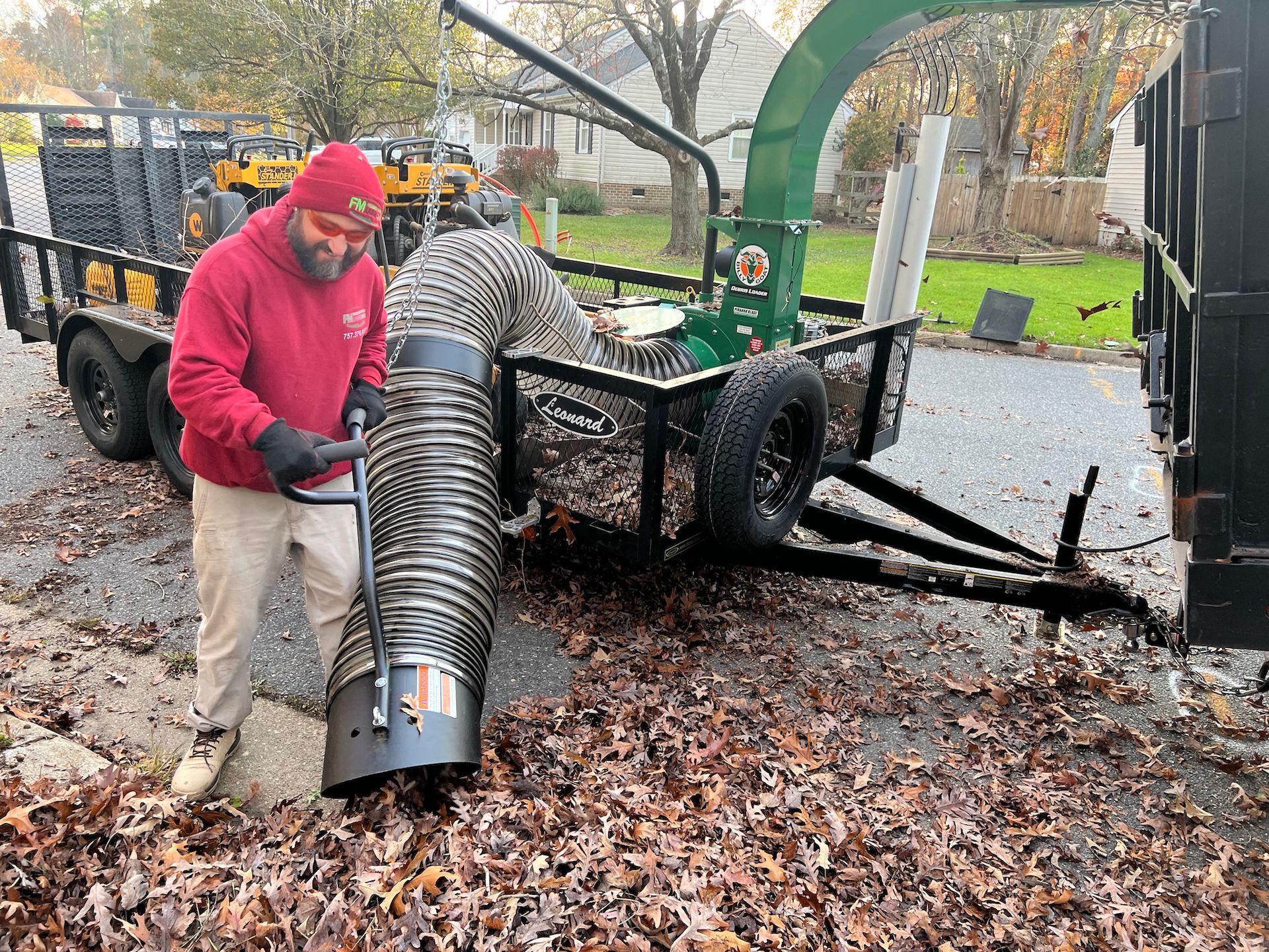 A man is using a hose to blow leaves from a trailer.