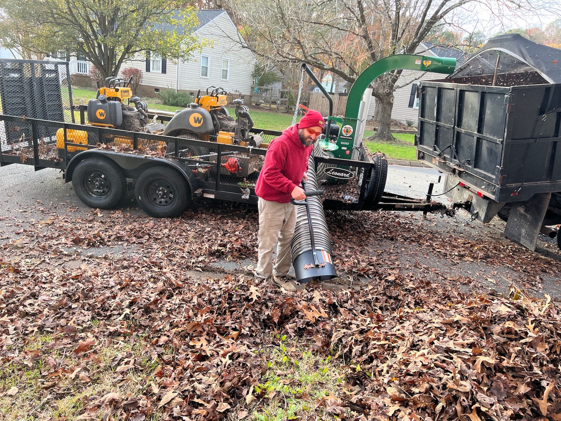 A man is blowing leaves from a trailer.