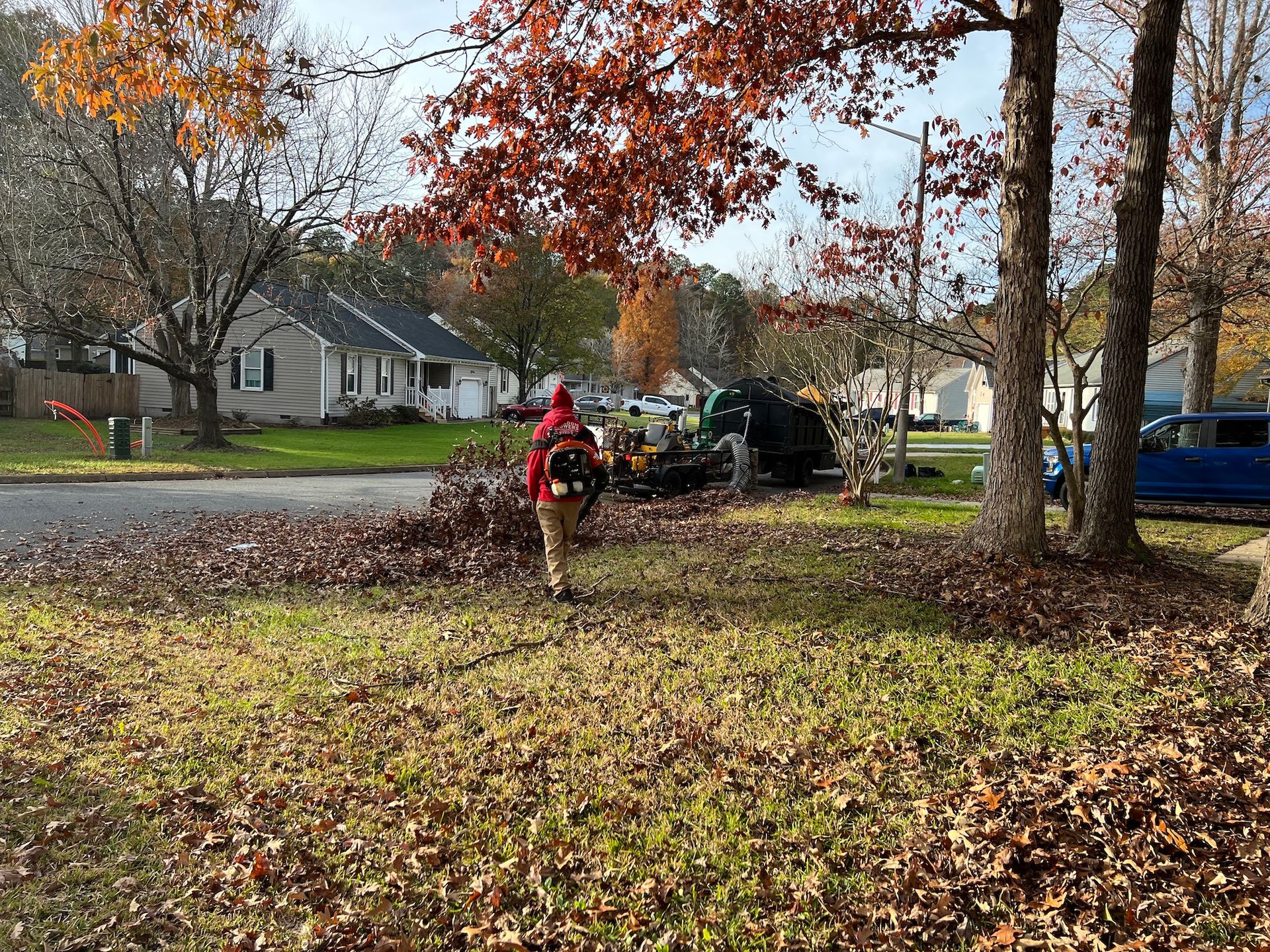 A man is blowing leaves in a yard with a leaf blower.