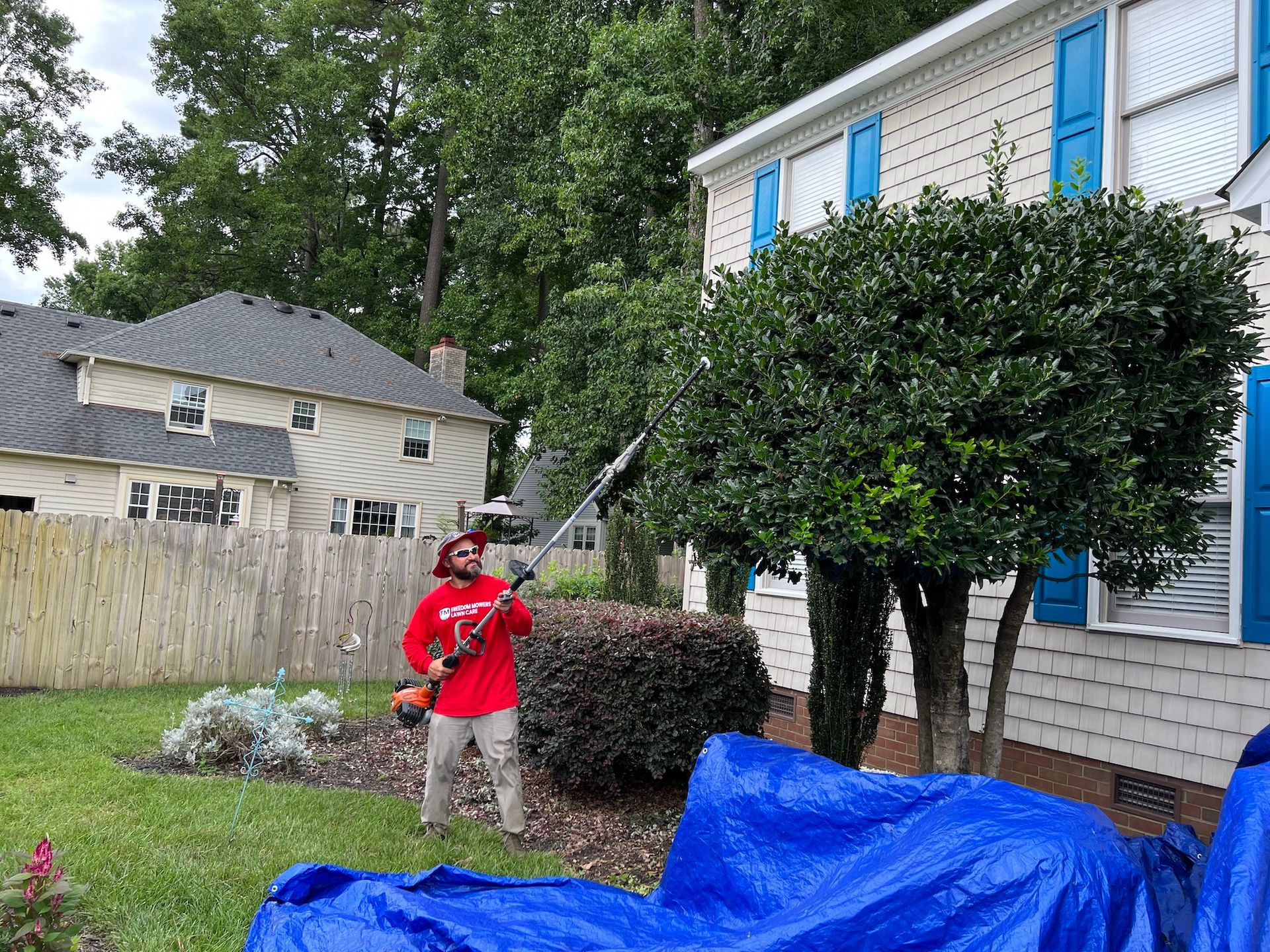 A man is standing in front of a house holding a lawn mower.