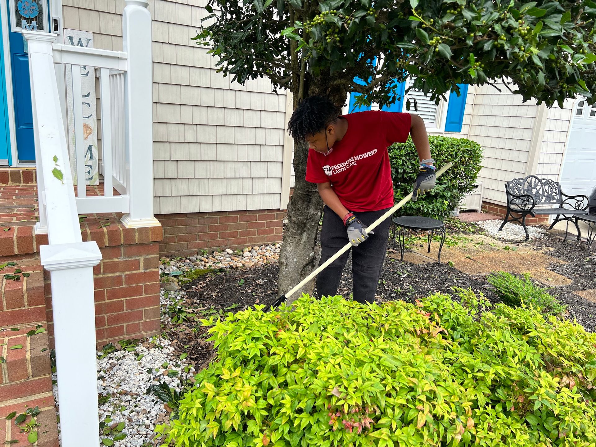 A man in a red shirt is raking a bush