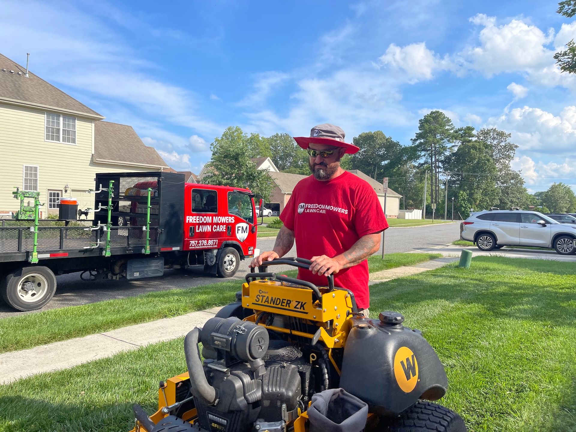 A man in a red shirt is standing next to a yellow lawn mower.