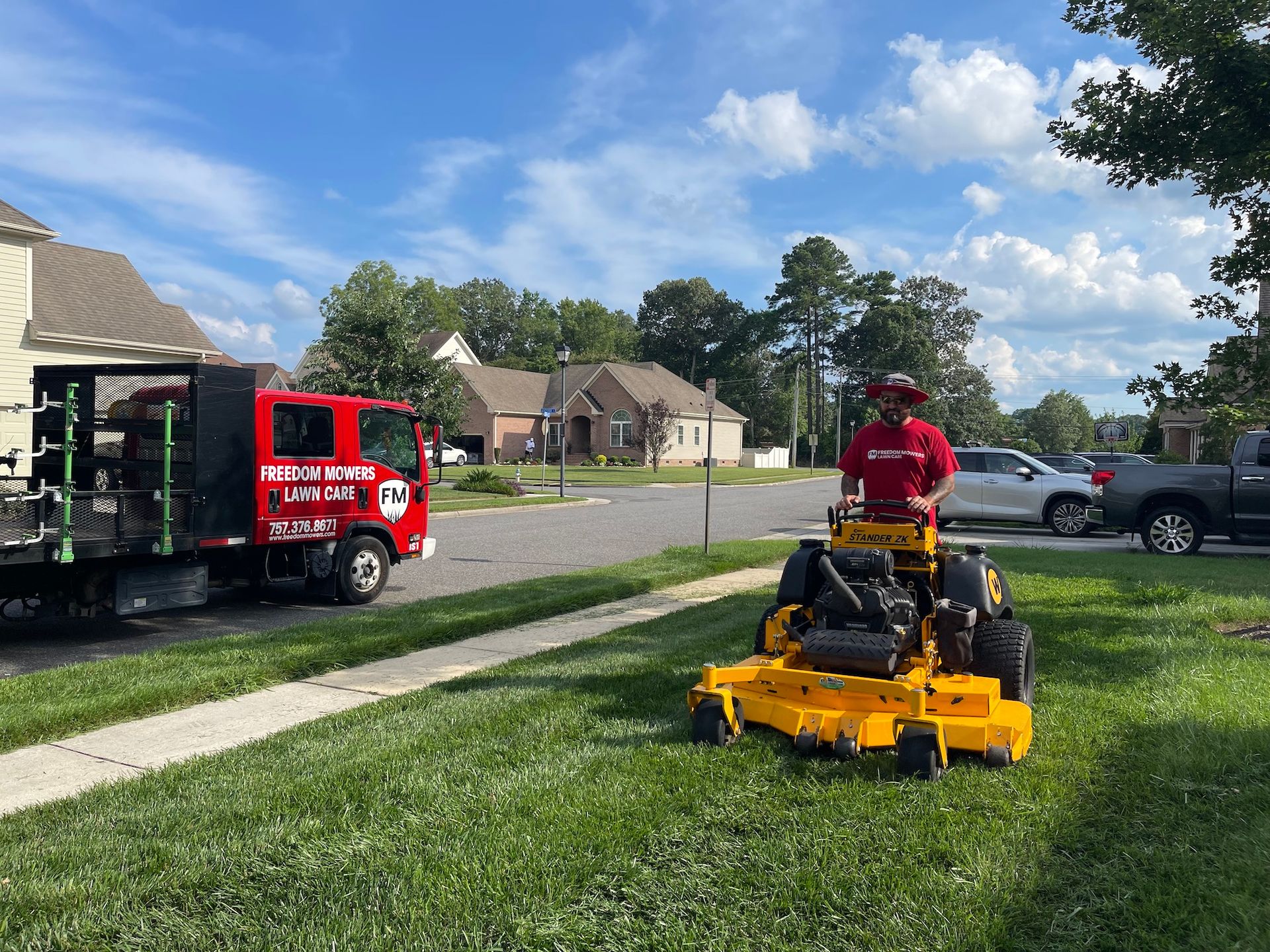 A man is riding a yellow lawn mower on a lush green lawn.