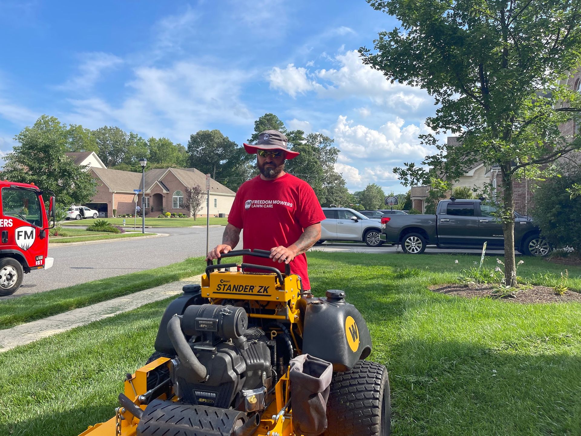 A man in a red shirt is riding a yellow lawn mower.