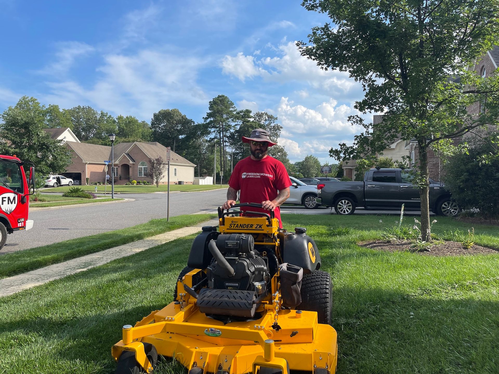 A man is riding a yellow lawn mower on a lush green lawn.