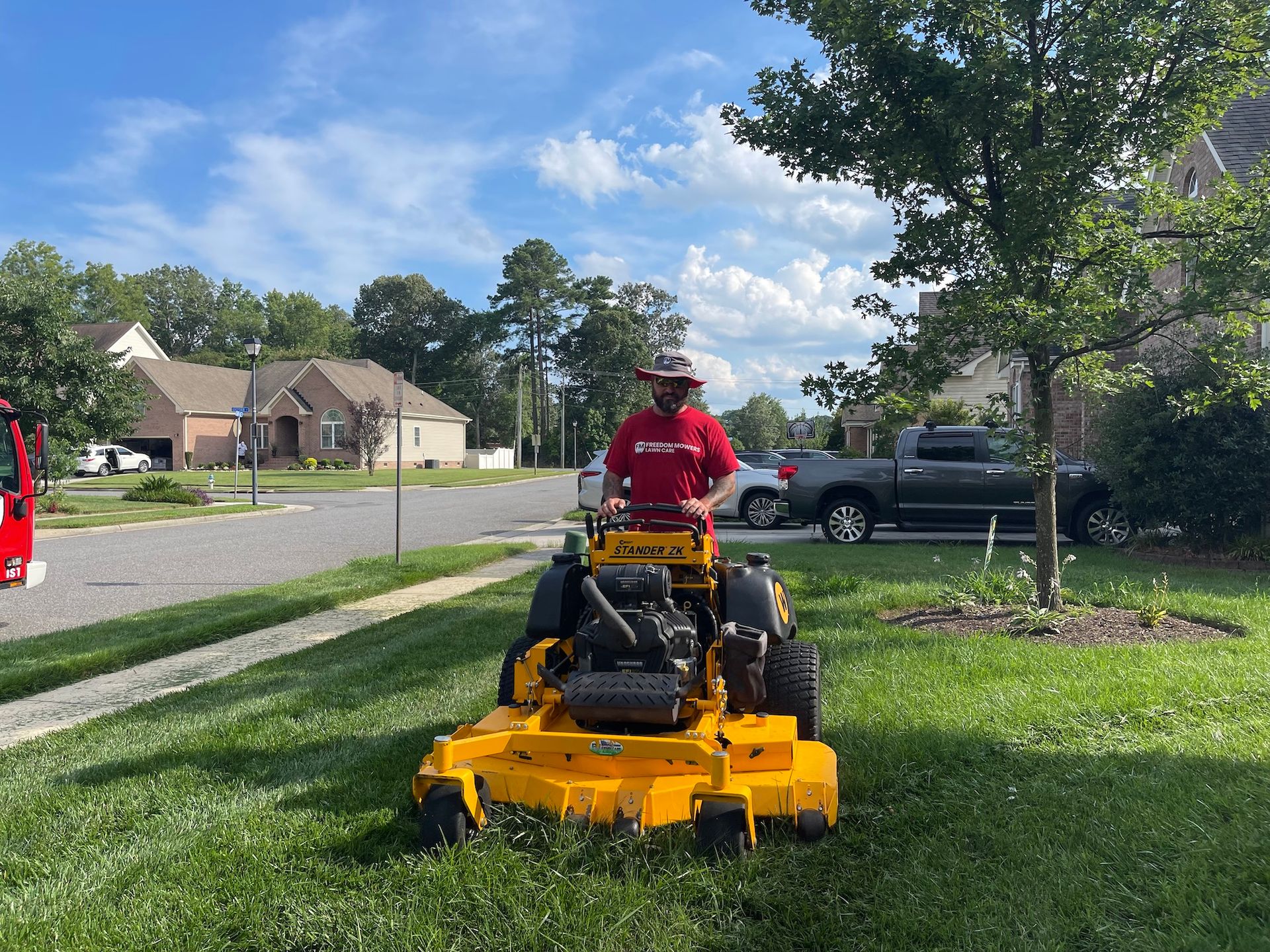 A man is riding a yellow lawn mower on a lush green lawn.