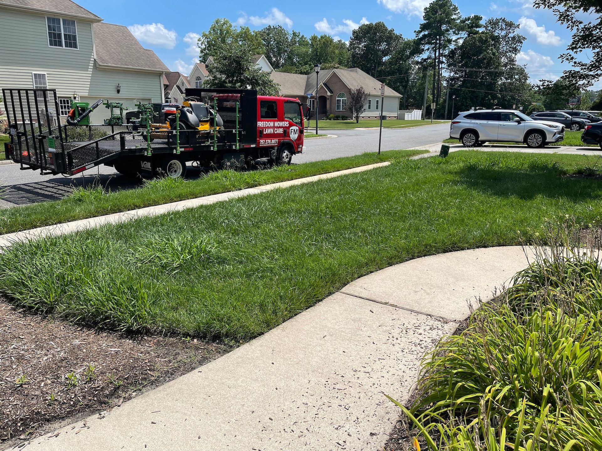 A red truck is parked on the side of the road next to a sidewalk.