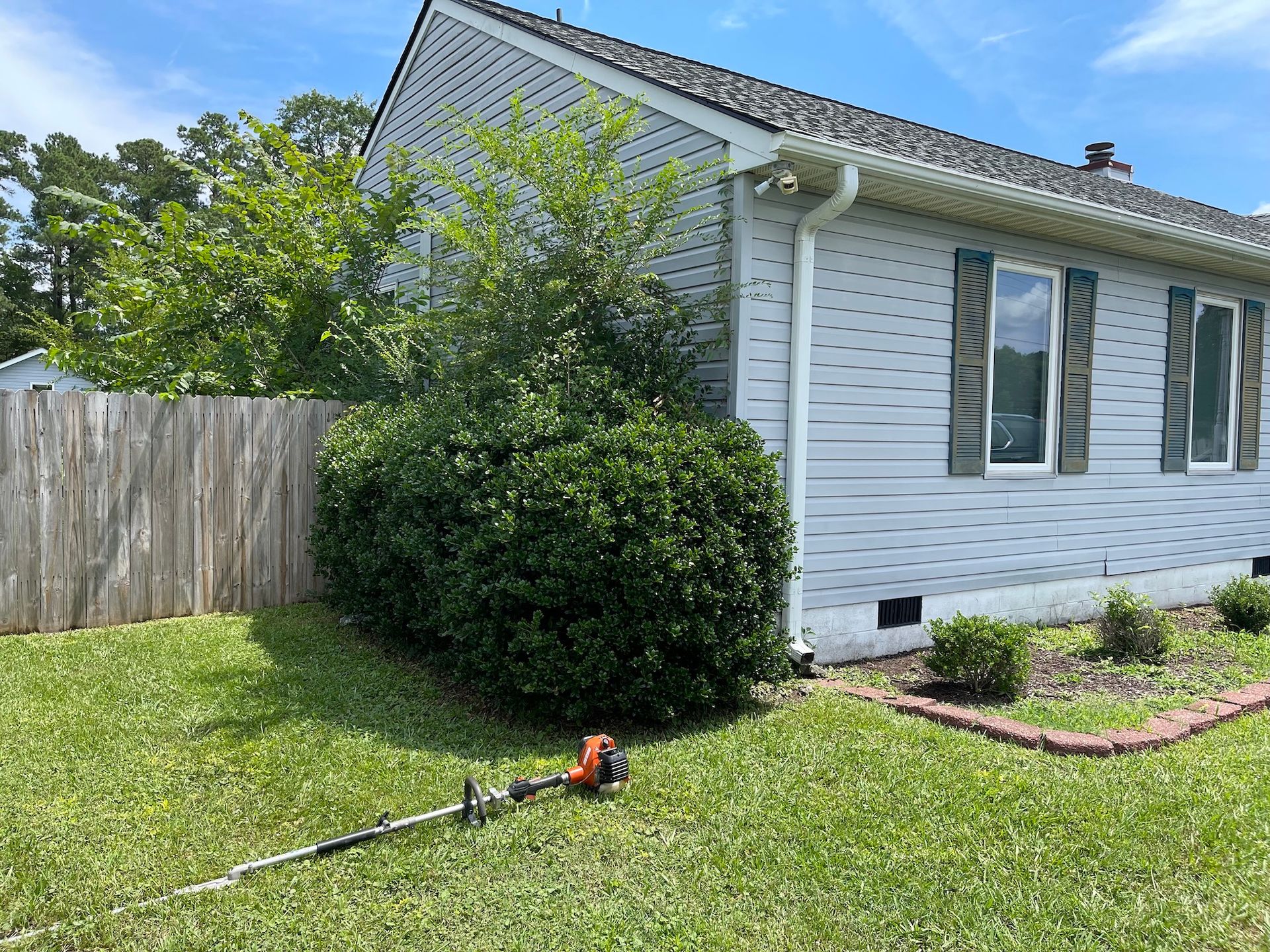 A lawn mower is sitting in the grass in front of a house.