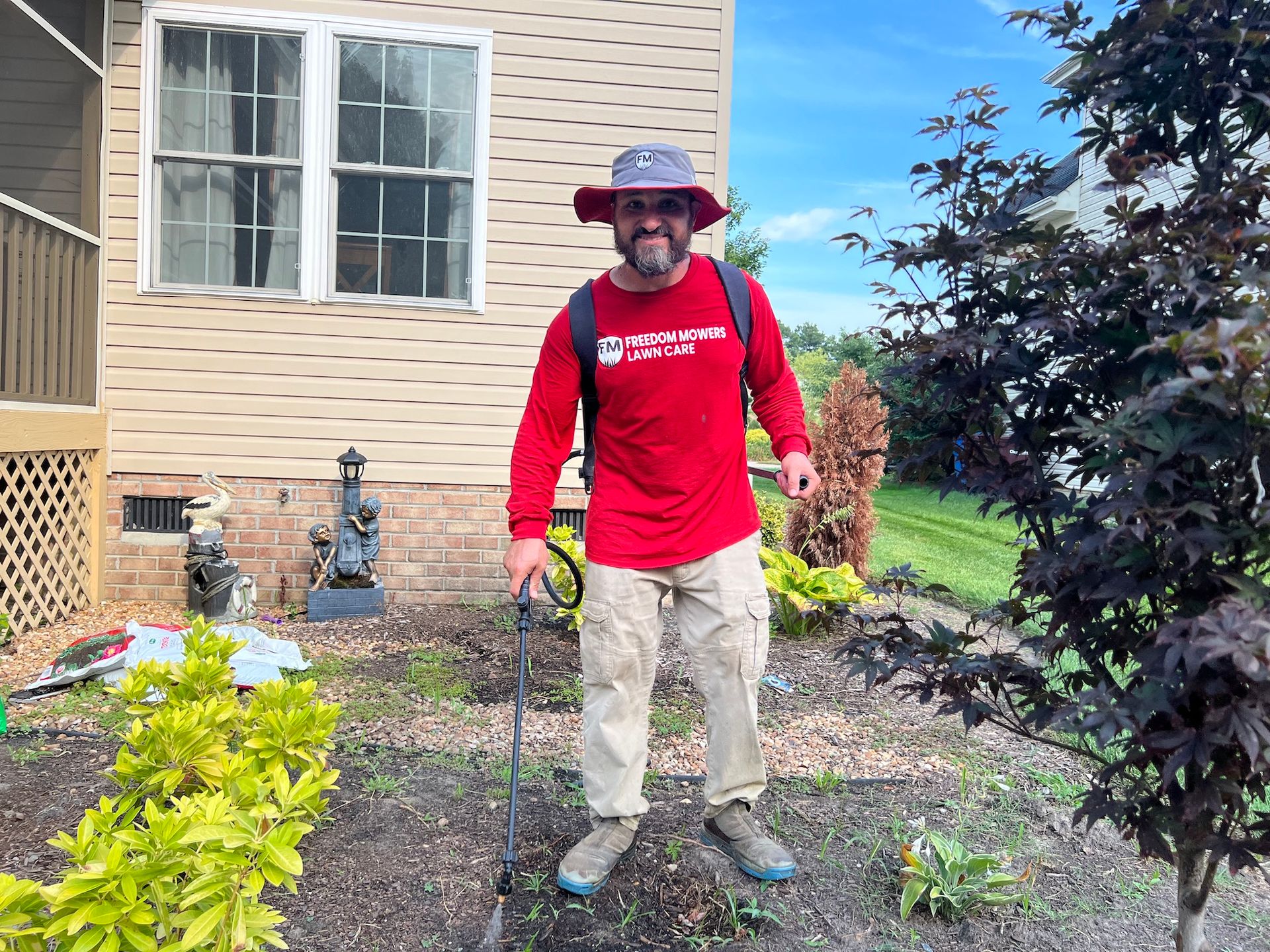 A man is standing in front of a house holding a metal detector.