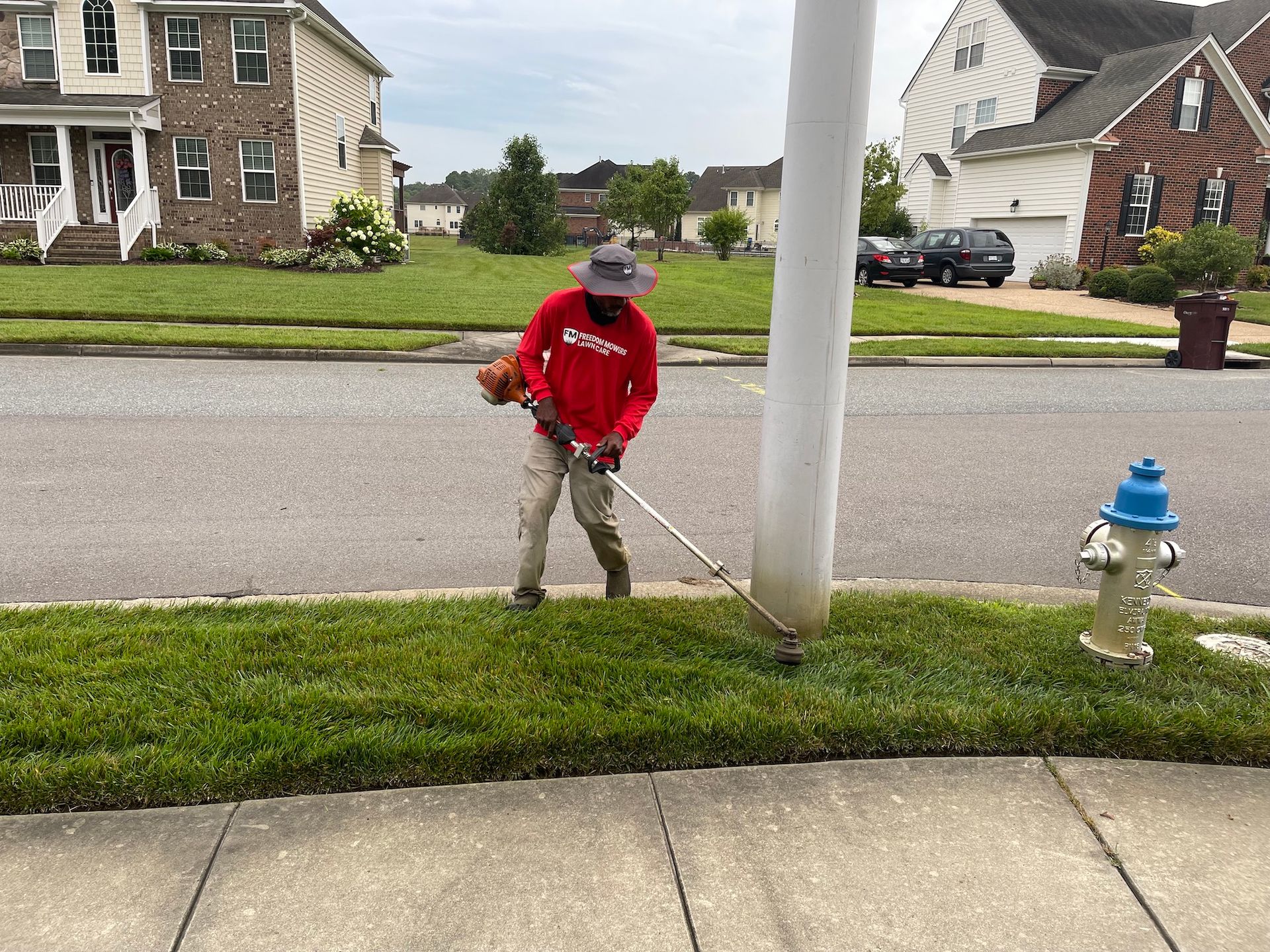 A man is mowing the grass in front of a fire hydrant.