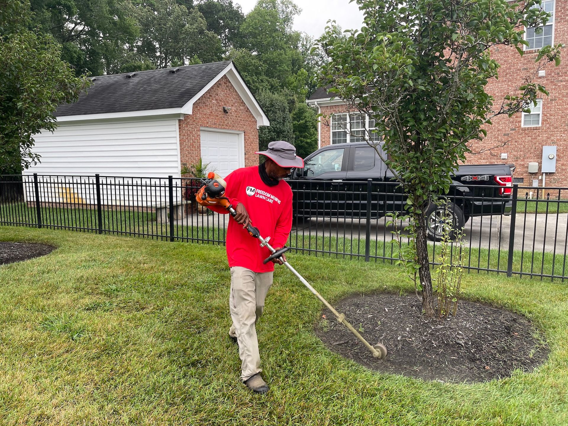 A man is cutting grass in a yard with a lawn mower.