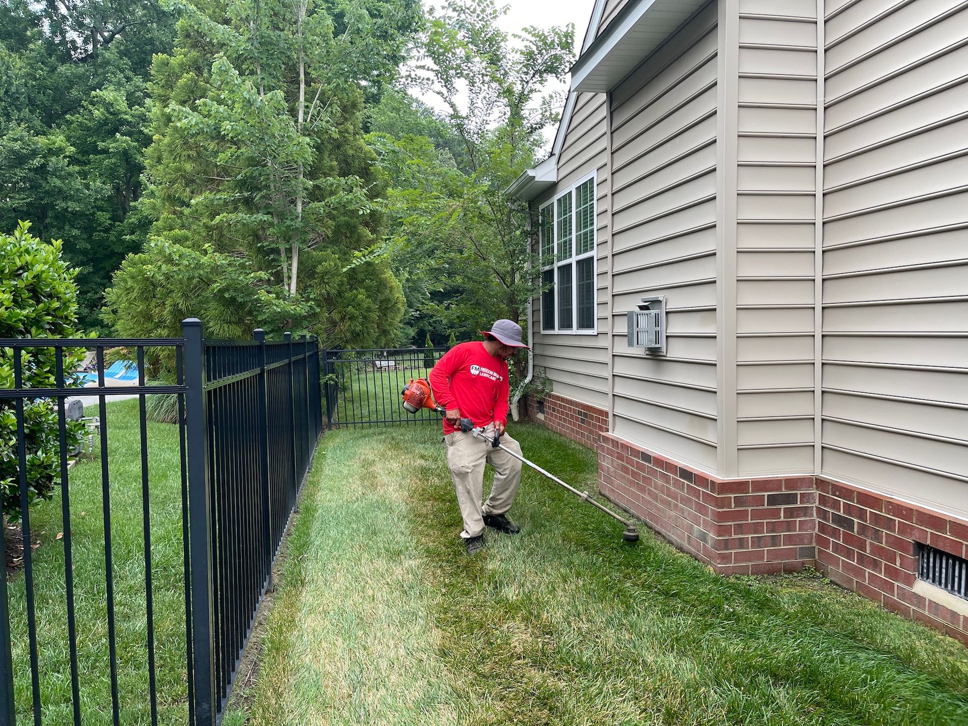 A man is mowing the grass in front of a house.