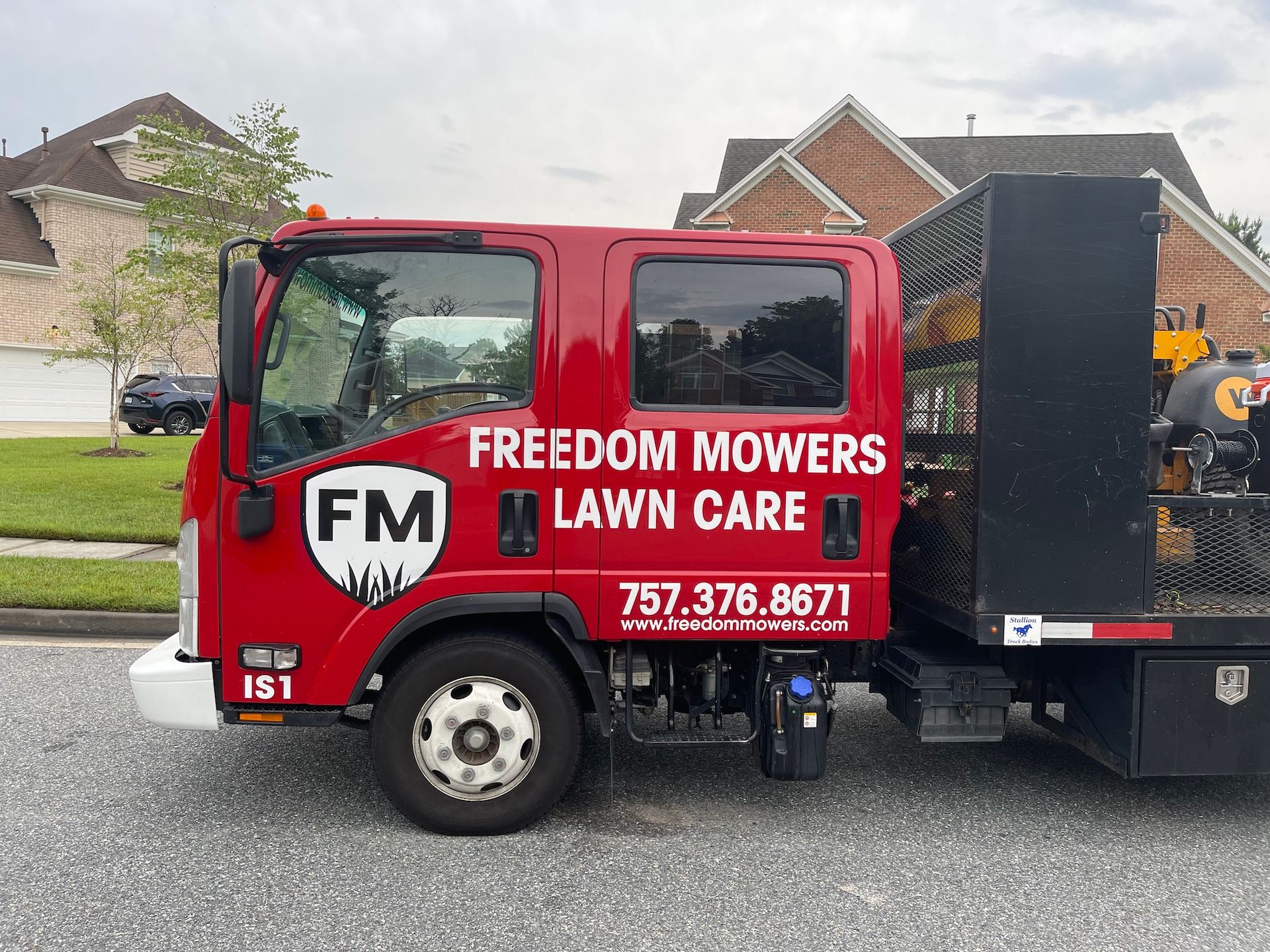 A red freedom mowers lawn care truck is parked on the side of the road.