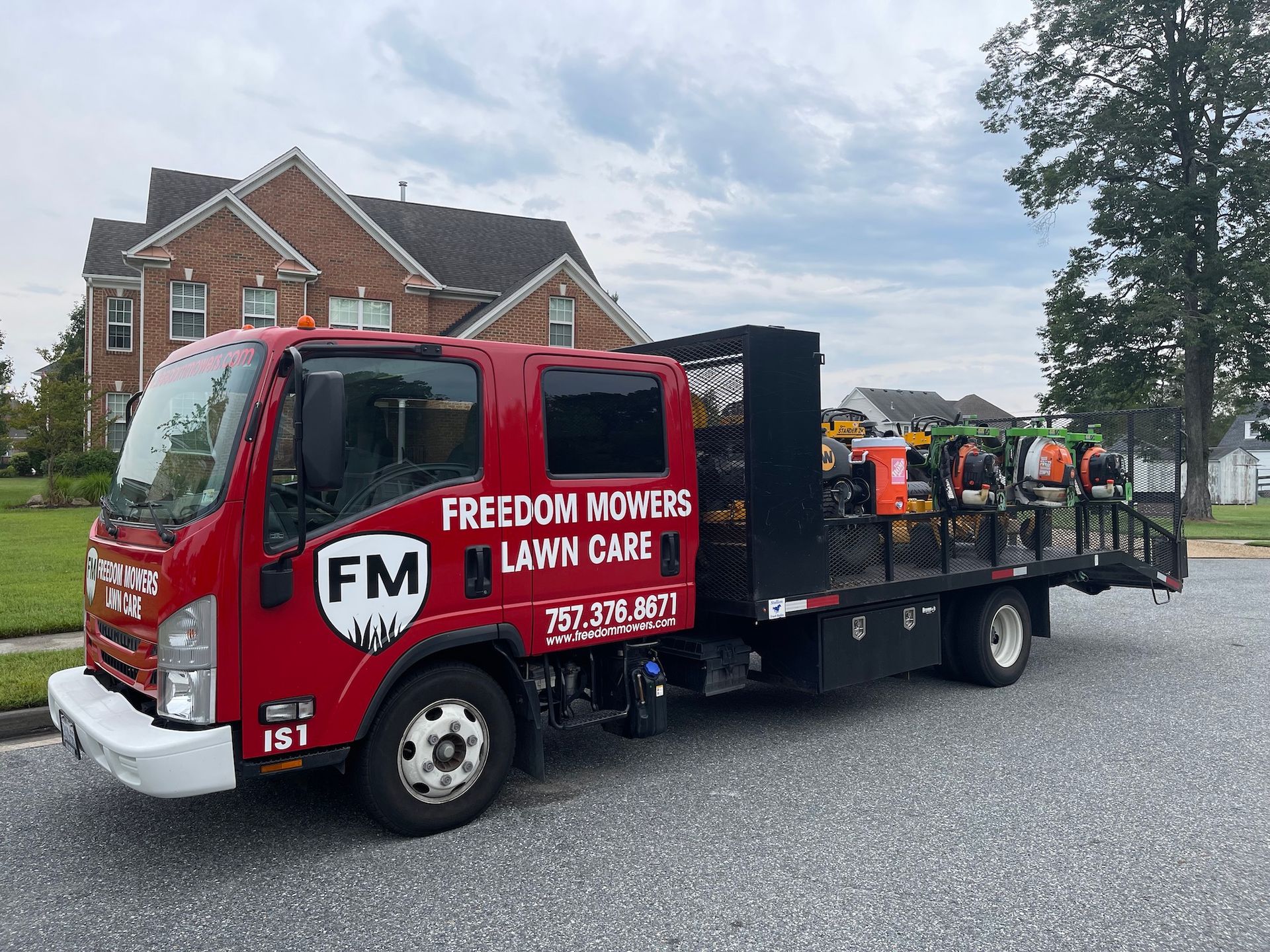 A red truck with a trailer attached to it is parked in front of a house.