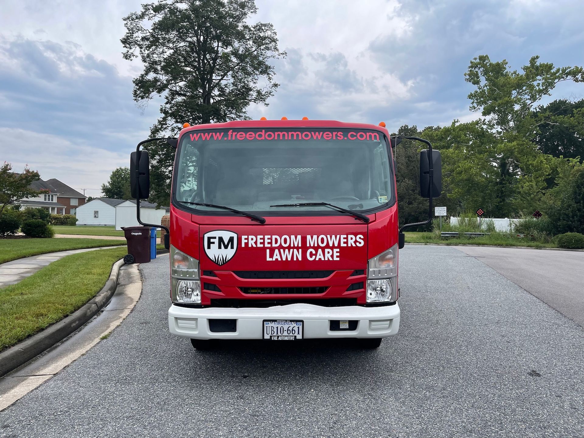 A red freedom mowers lawn care truck is parked on the side of the road.