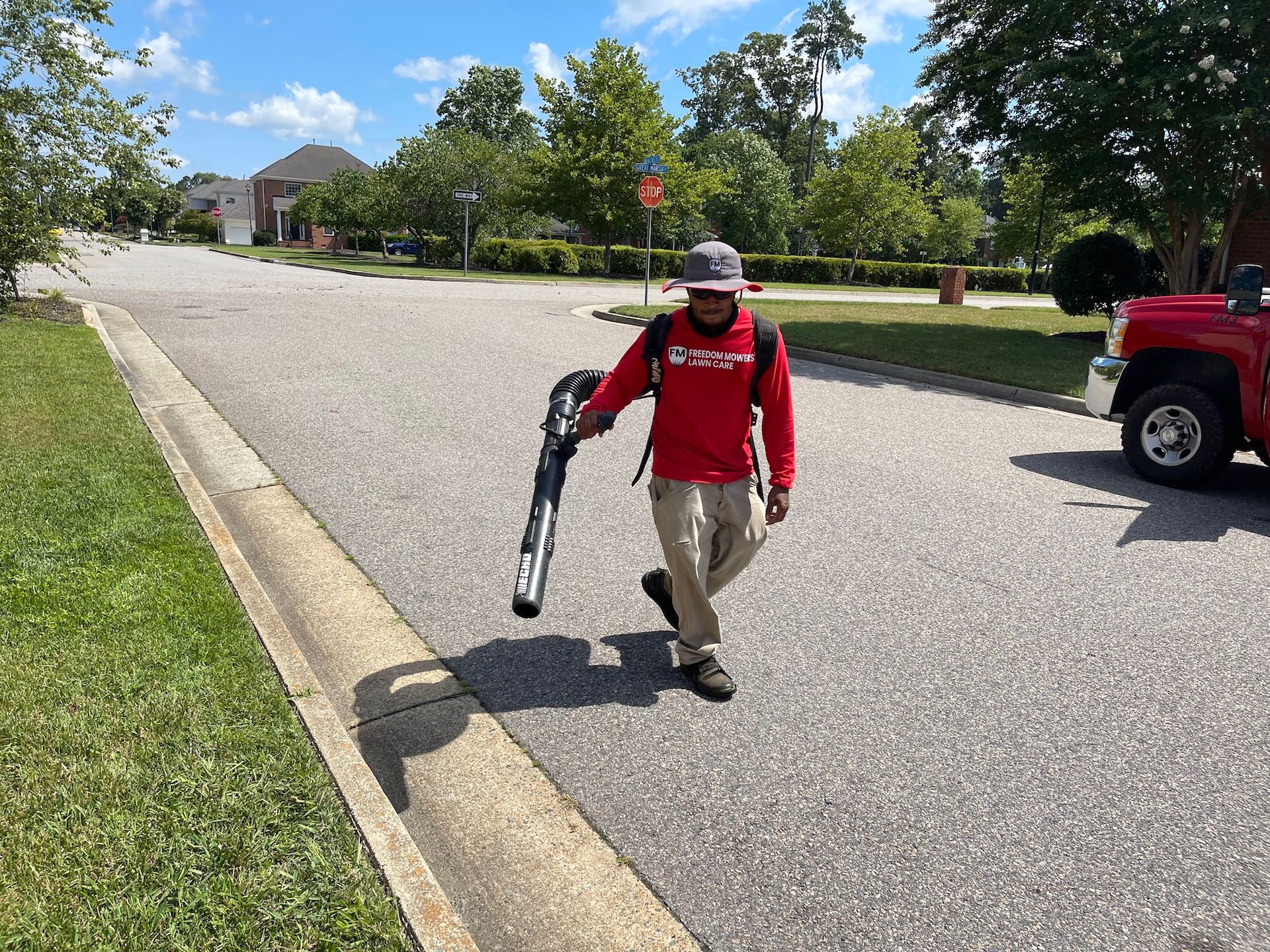 A man is walking down a street holding a blower.