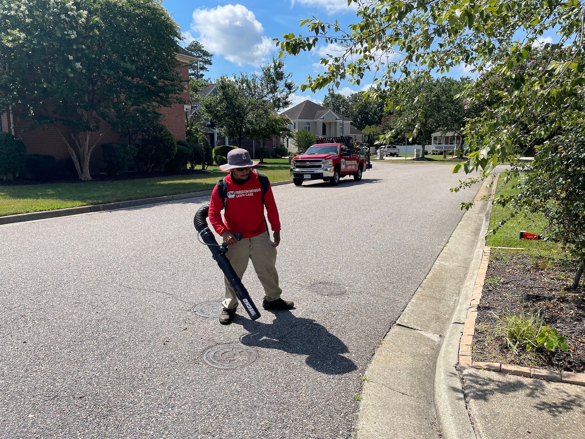 A man is standing on the side of the road holding a blower.