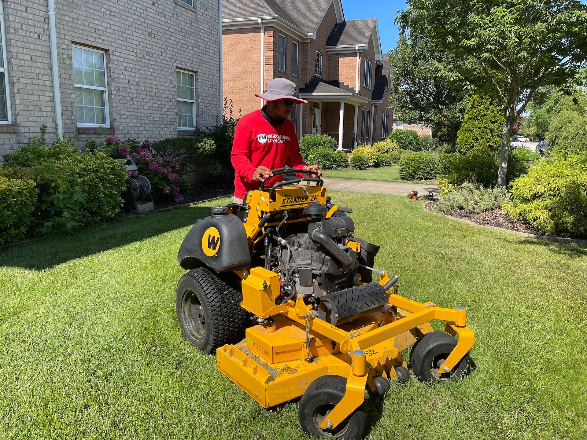 A man is riding a yellow lawn mower on a lush green lawn.