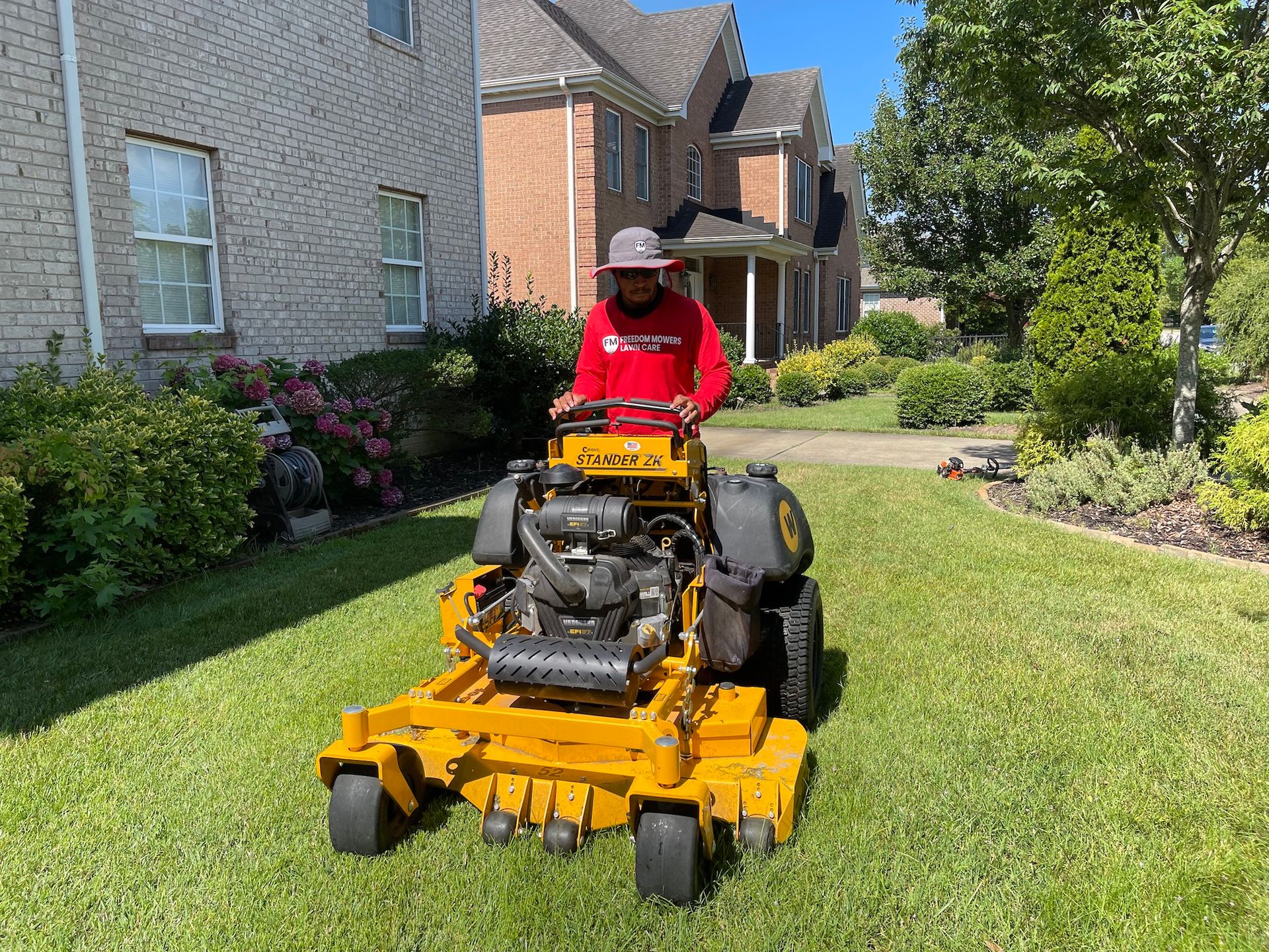 A man is riding a yellow lawn mower in front of a house.