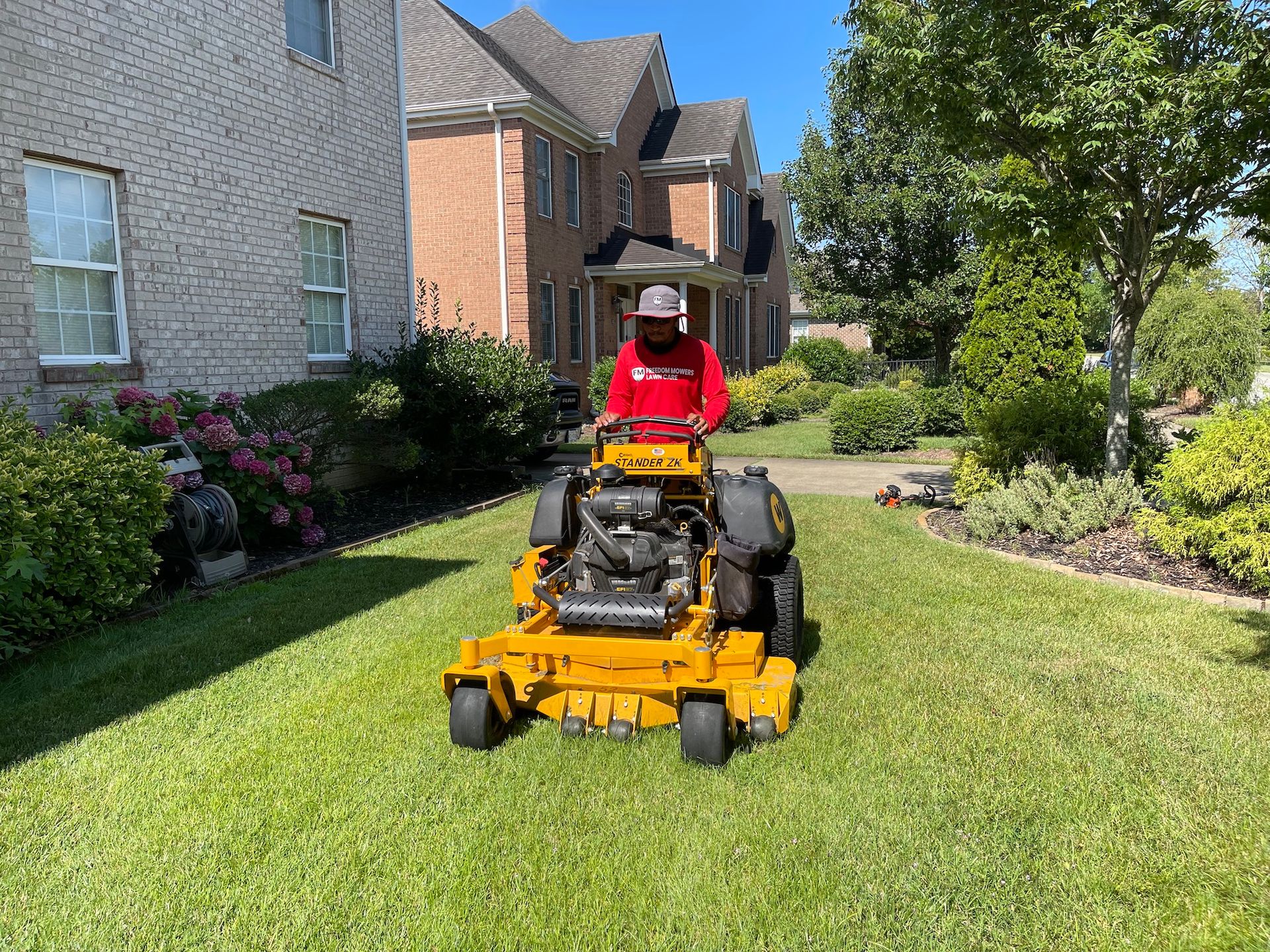 A man is riding a yellow lawn mower on a lush green lawn.