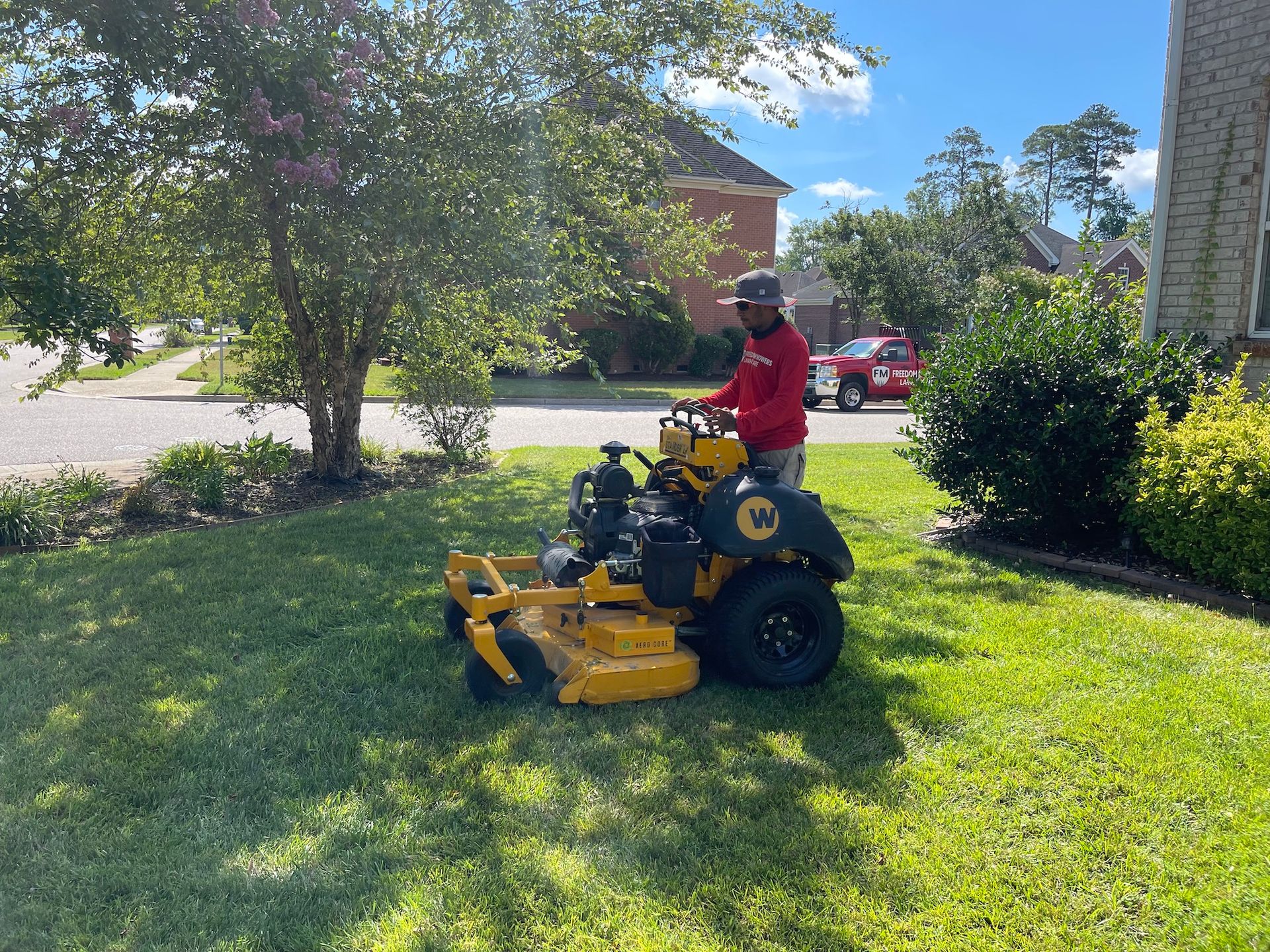 A man is riding a yellow lawn mower on a lush green lawn.