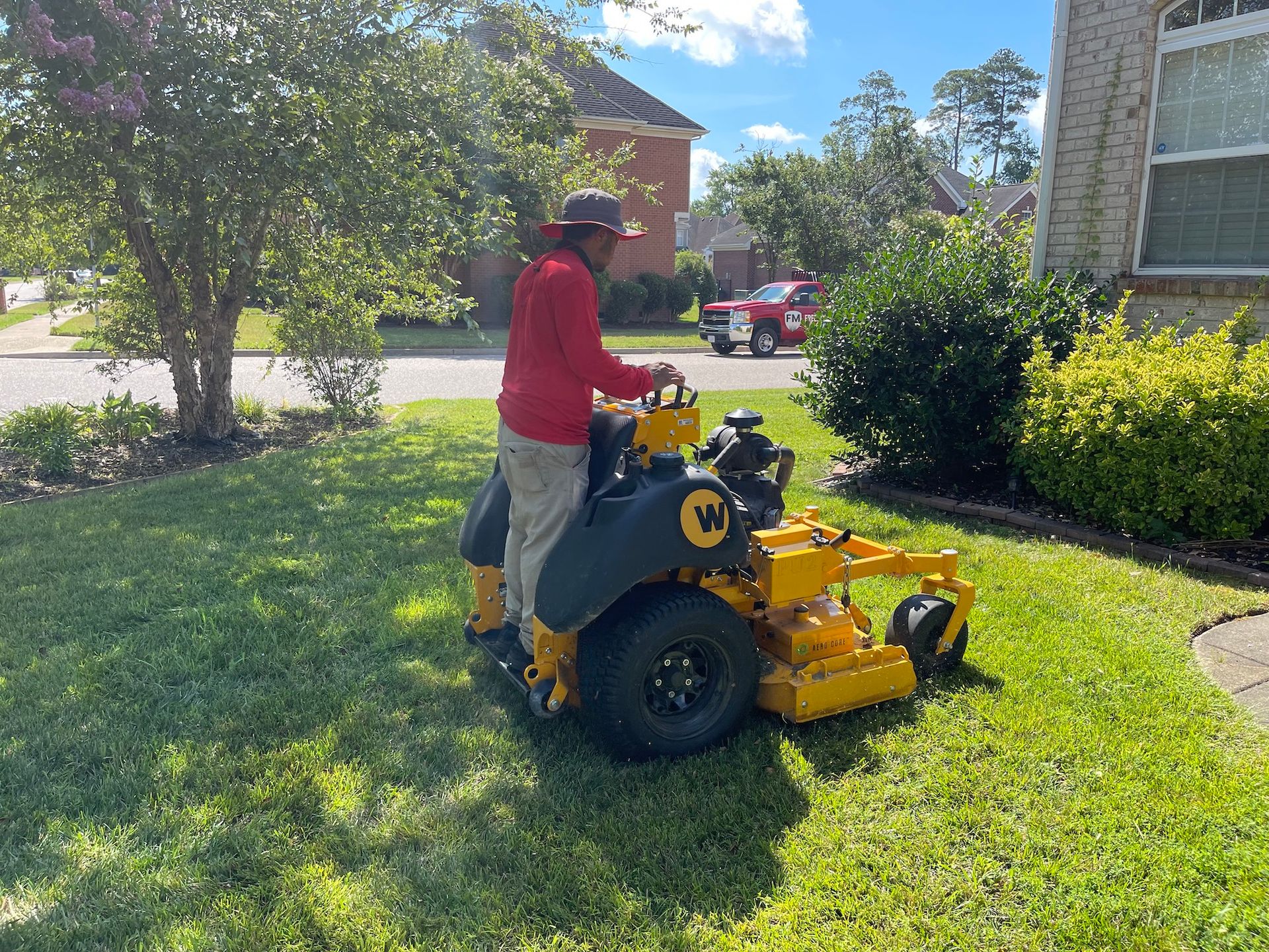 A man is riding a yellow lawn mower on a lush green lawn.