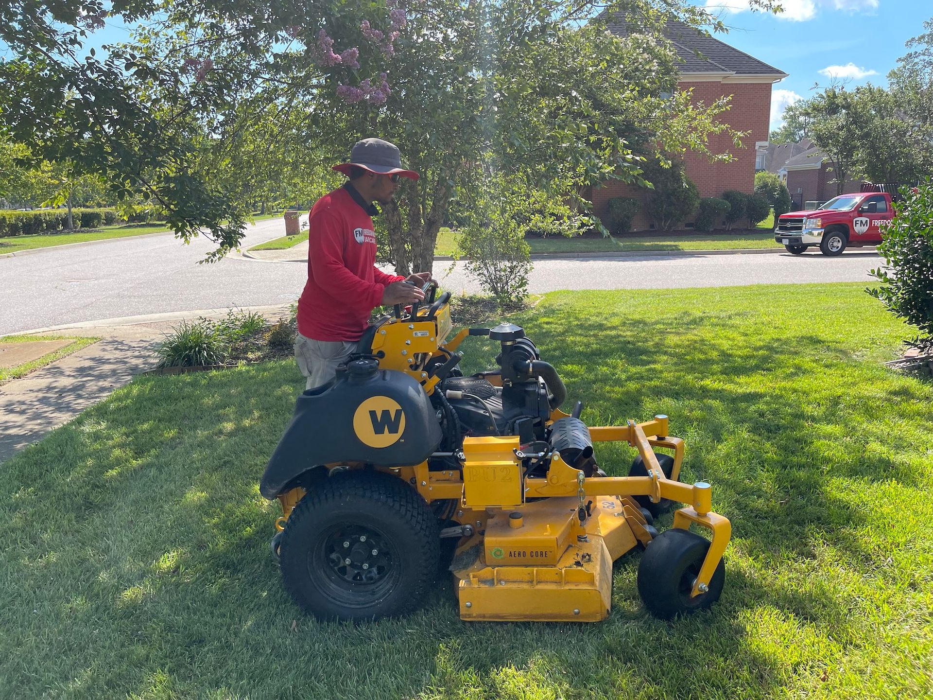 A man is riding a yellow lawn mower on a lush green lawn.