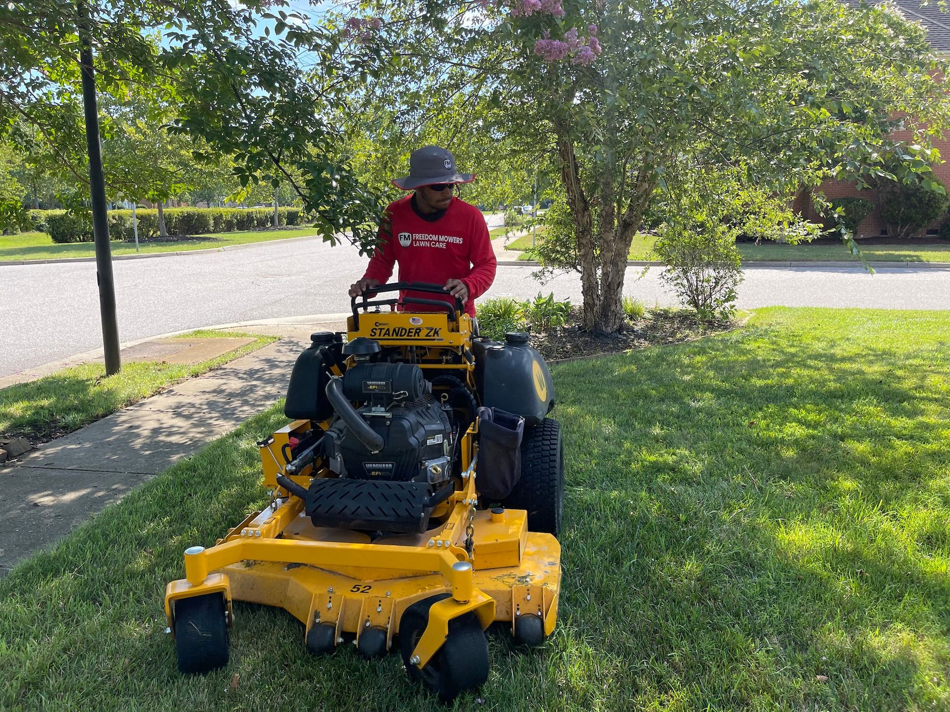 A man is riding a yellow lawn mower on a lush green lawn.