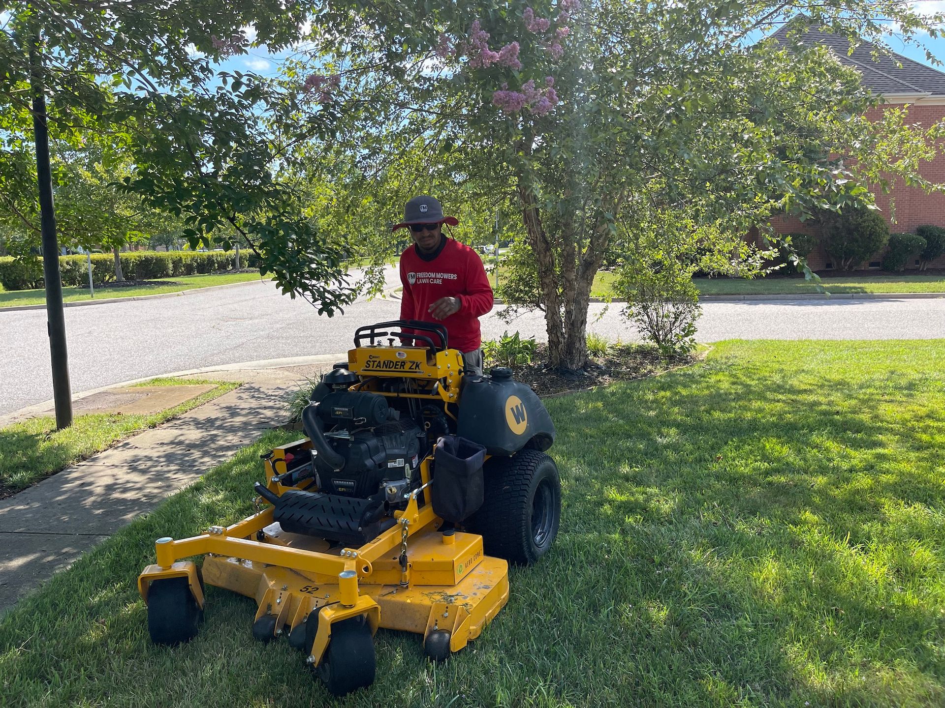 A man is riding a yellow lawn mower on a lush green lawn.