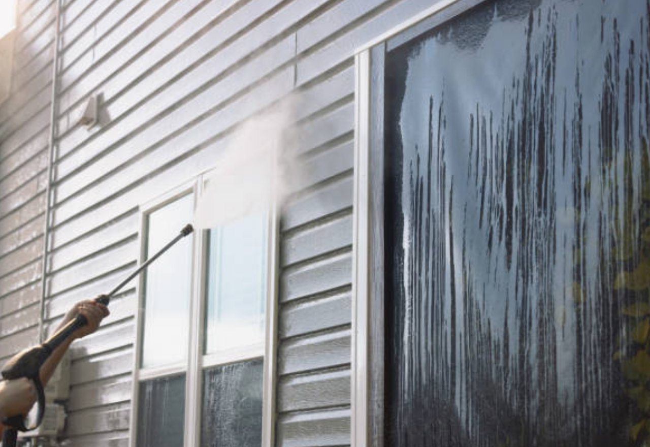 TruStrong Services worker power washing house siding and windows