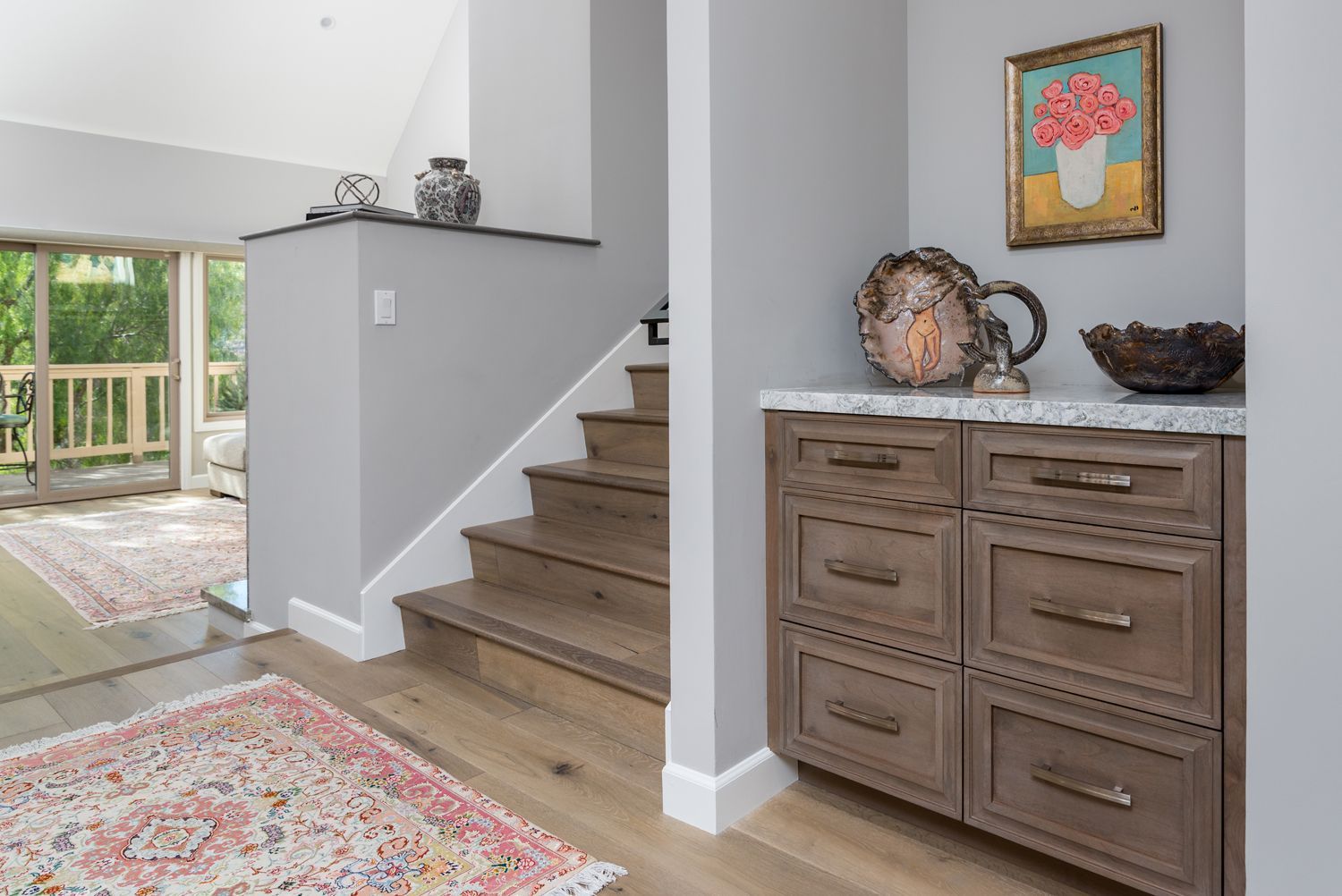 image shows the entry way of a home with medium brown cabinetry & hardwood flooring 