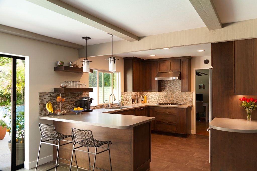 Modern kitchen with island seating, wood cabinets, stone countertops, and large window with flowers