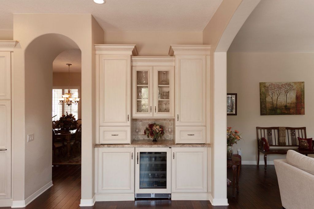 Elegant living room with built-in white cabinets, wine cooler, arches, and hardwood floors
