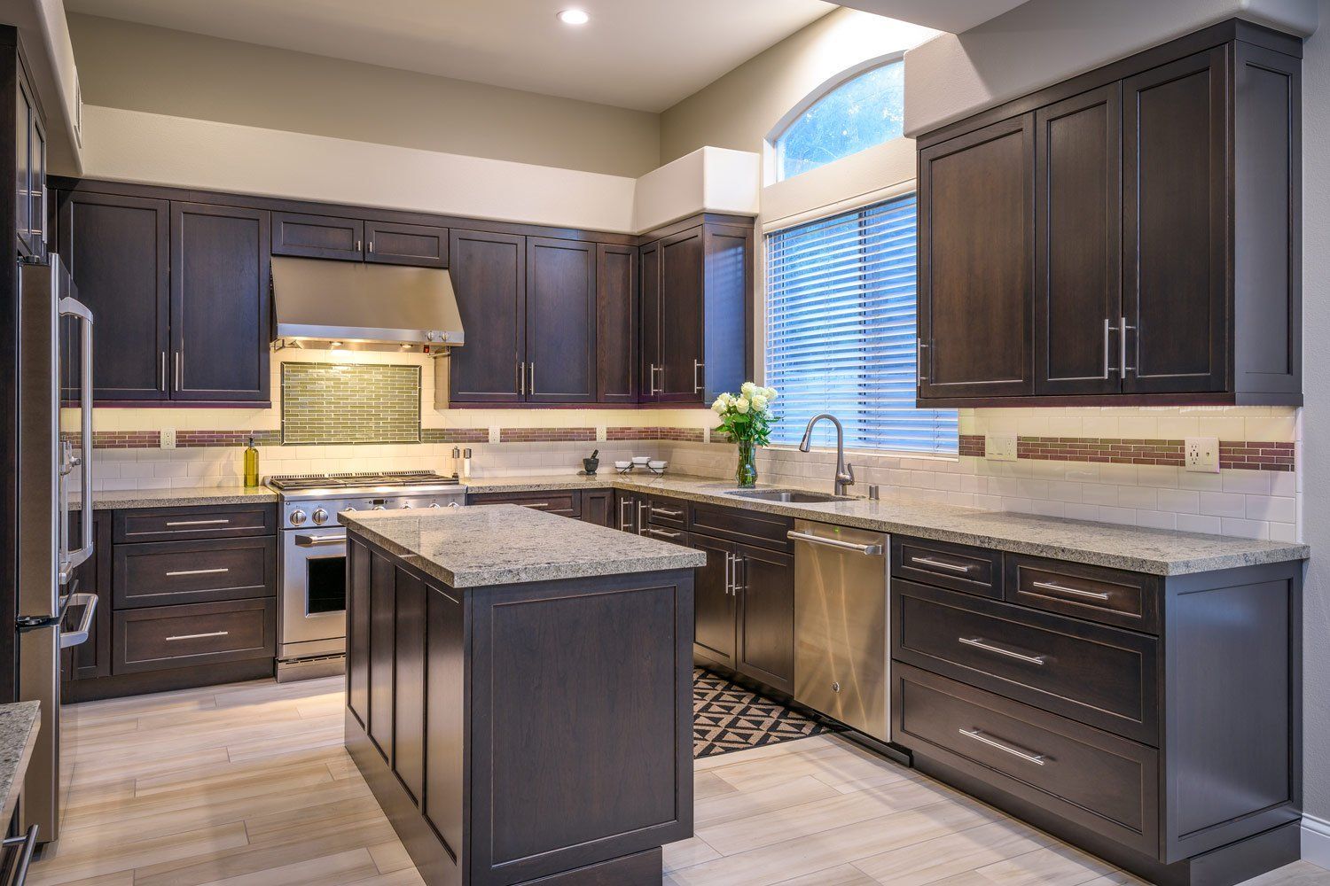 Modern kitchen with dark cabinets, granite island, stainless appliances, and a window over the sink