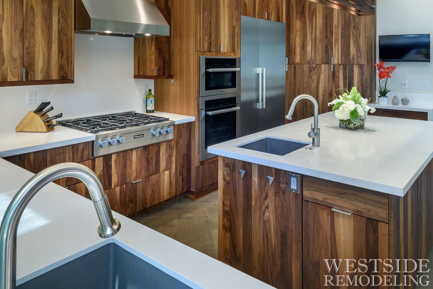 Modern kitchen with wood cabinets, stainless appliances, white island, and chrome faucet