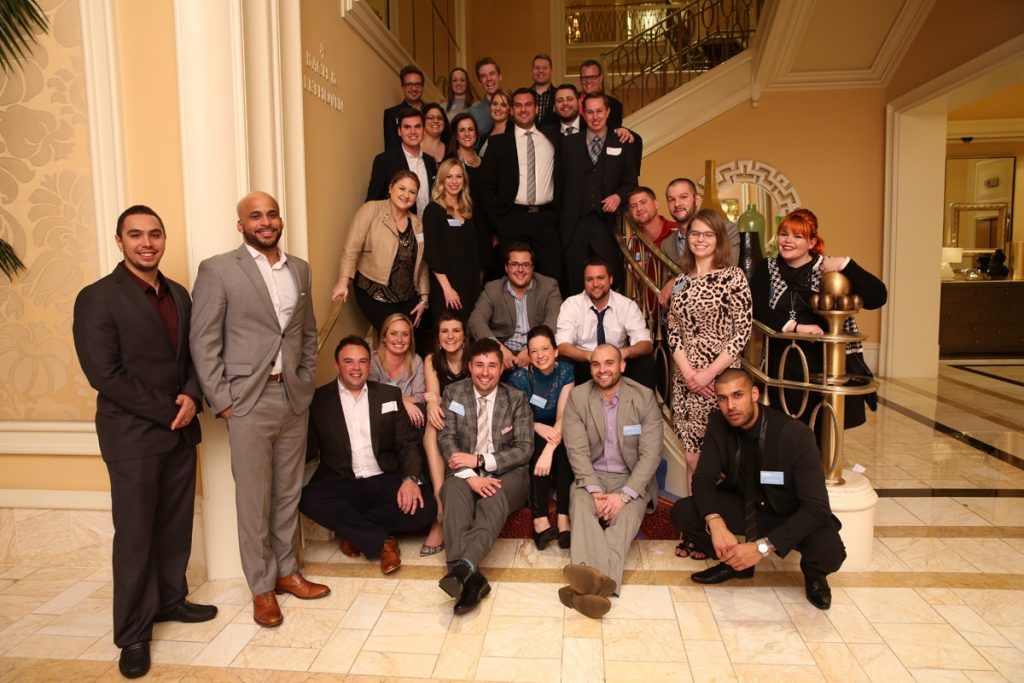 Large group posing on a grand staircase in a hotel lobby during a formal event
