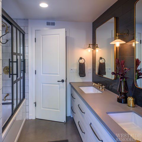 Modern bathroom with double vanity, large mirror, white door, and glass shower enclosure