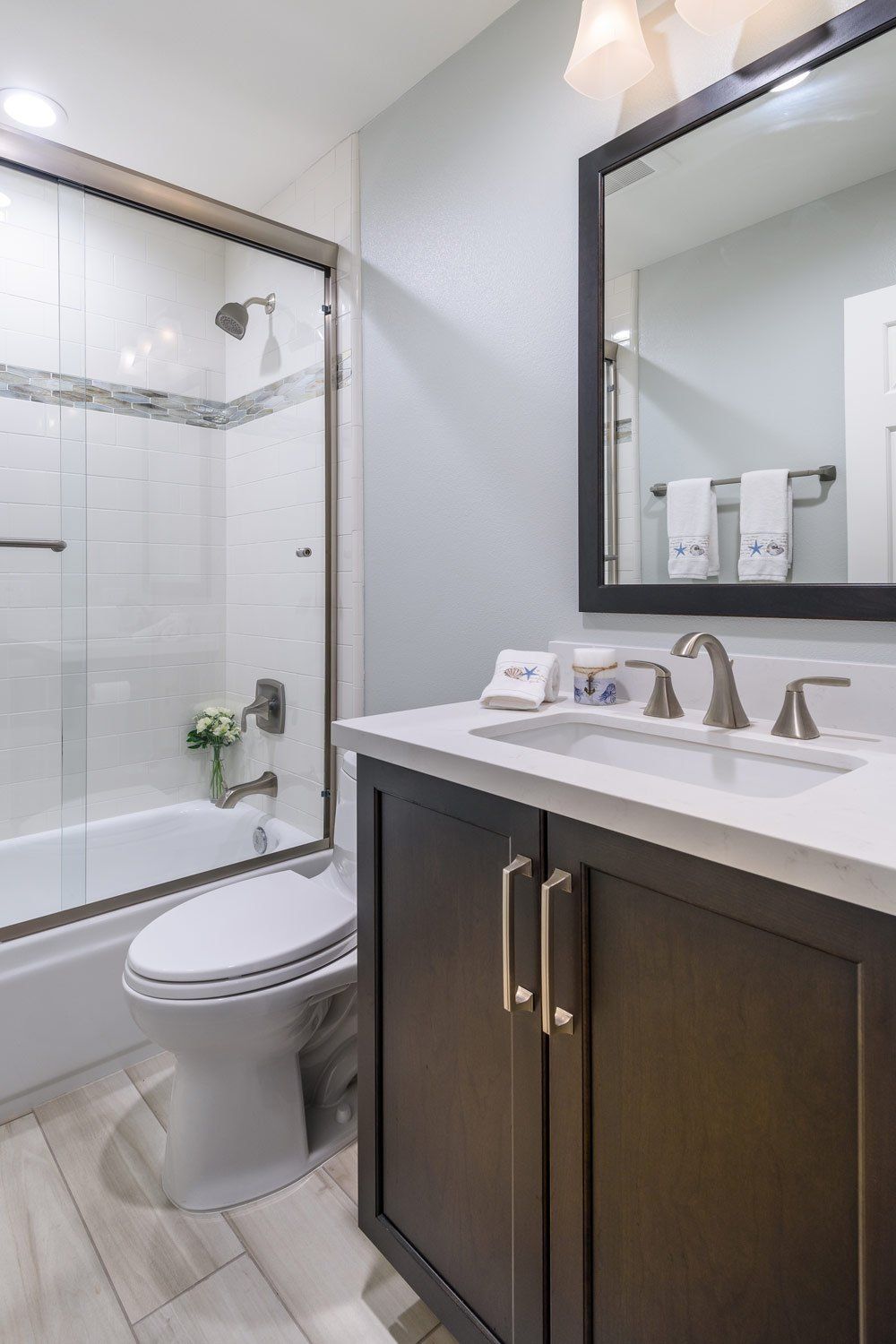 Modern bathroom with a toilet, glass shower, dark vanity, and large mirror