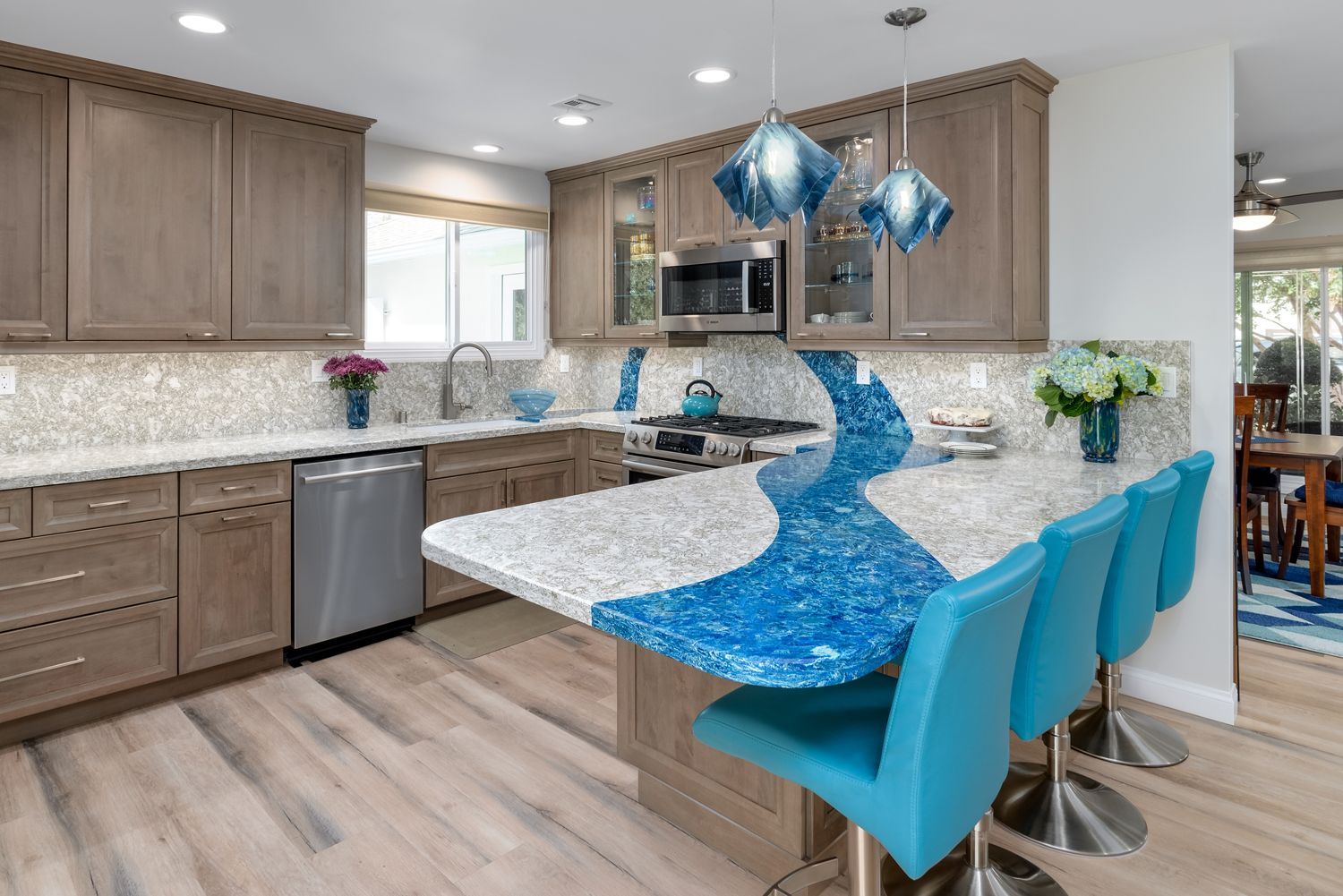 Modern kitchen with light wood cabinets, white island, and bright blue chairs and decor