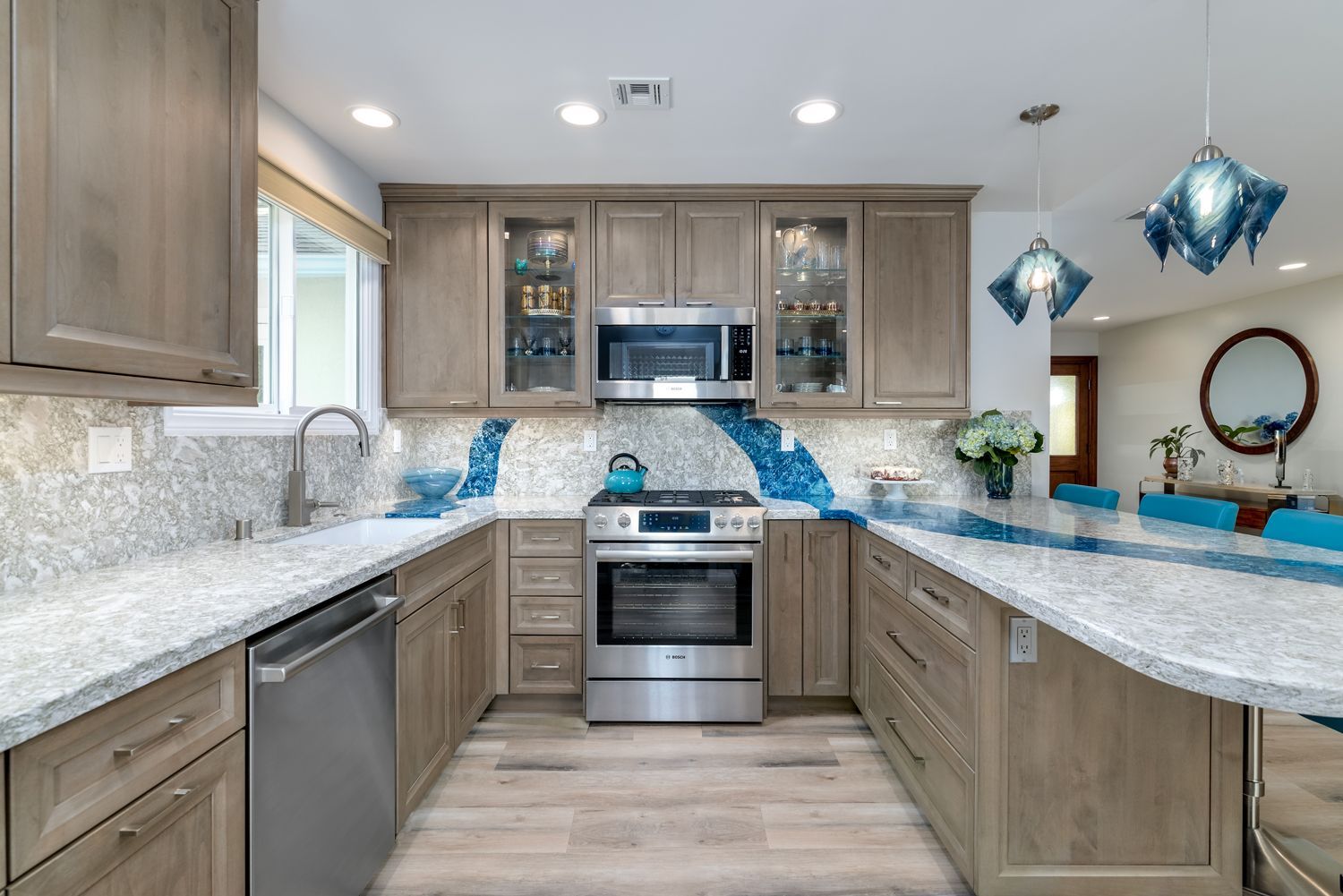 Modern kitchen with gray cabinets, white countertops, stainless appliances, and blue tile backsplash