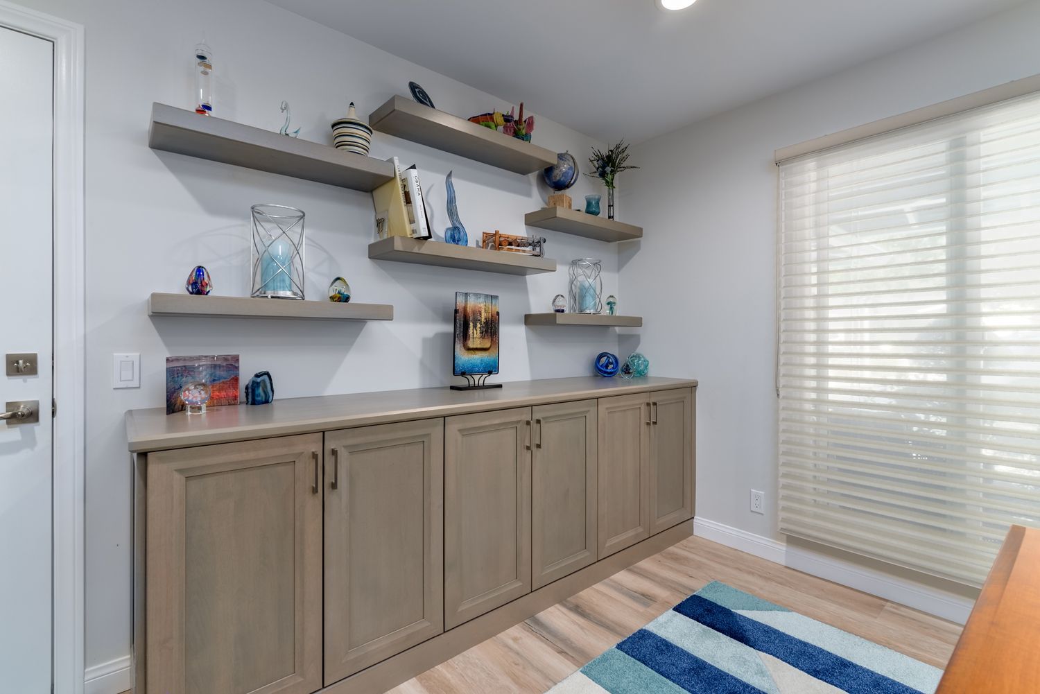 image shows light colored wood cabinetry and floating shelves with decorations in dining room, Whole House Remodel, West Hills, CA 