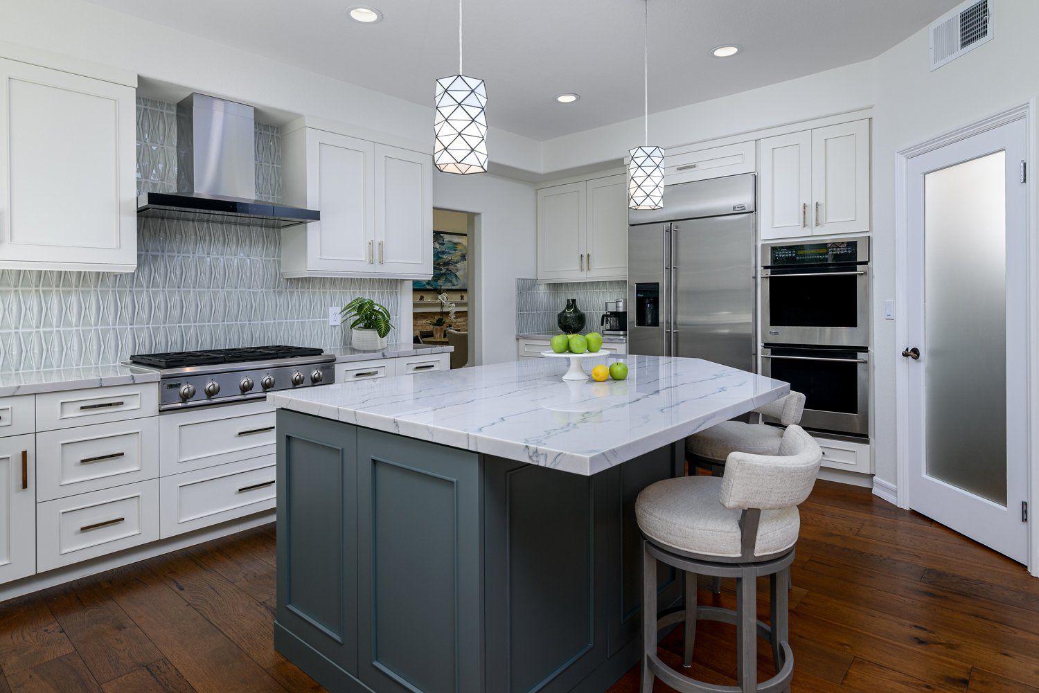 Bright modern kitchen with white cabinets, marble island, stainless appliances, and dark wood floors