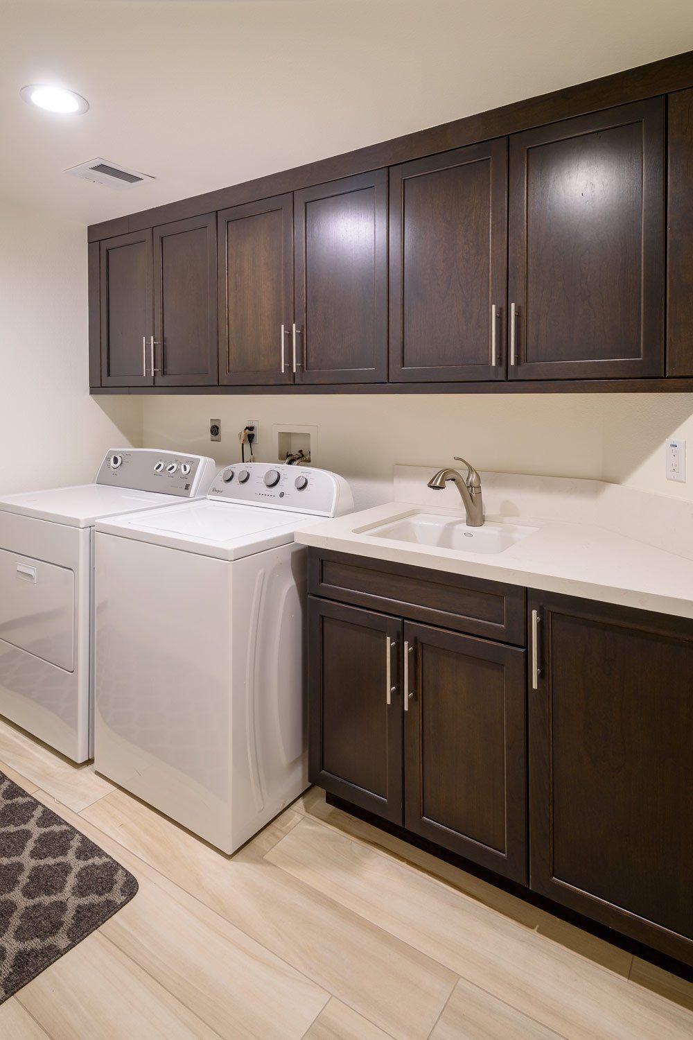 Laundry room with white washer and dryer, dark cabinets, and a light countertop.