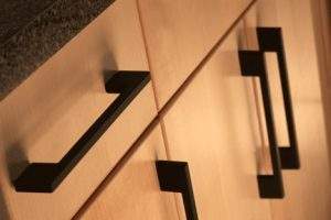 Close-up of black wall-mounted house number signs on a light wooden surface