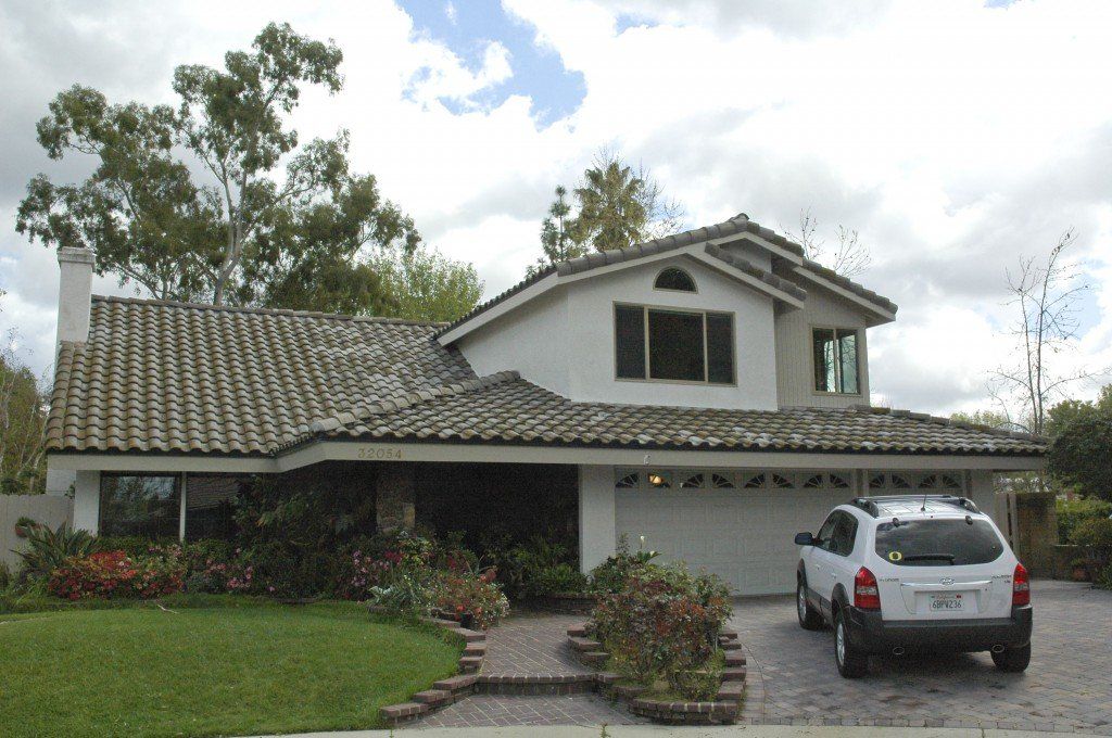 Suburban house with a tiled roof, front garden, and silver SUV parked in the driveway