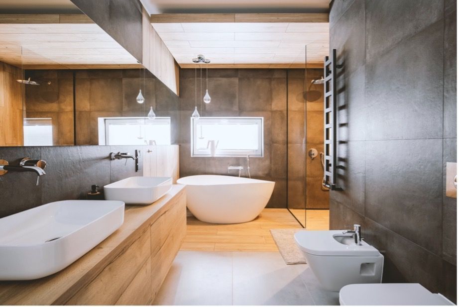 Modern bathroom with wood paneling, freestanding tub, double sinks, and a bidet beside a large window