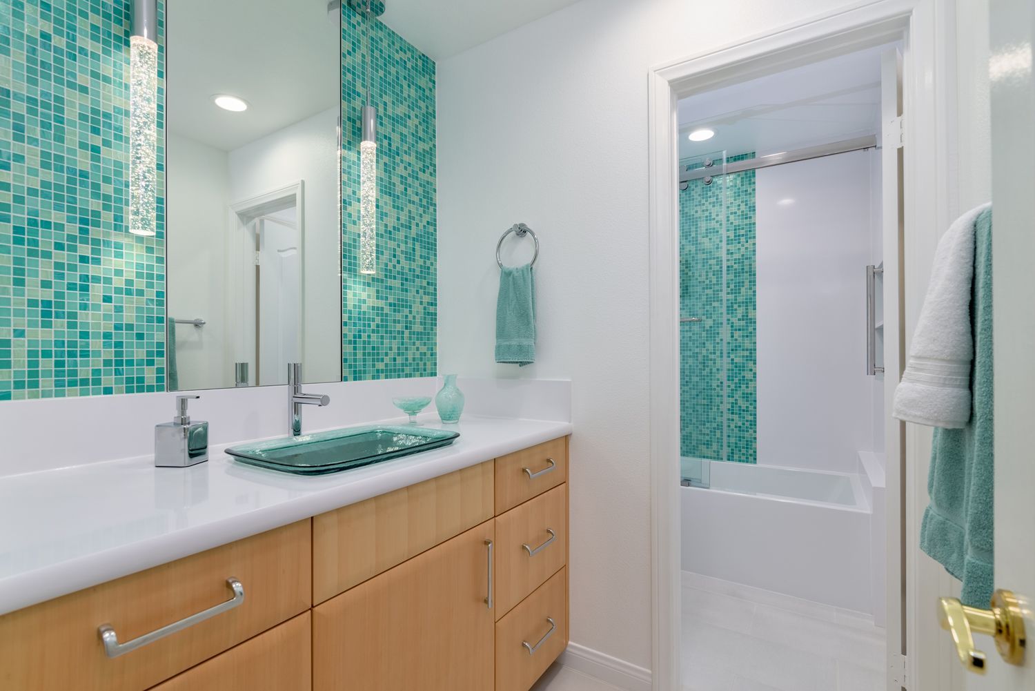 Modern bathroom with teal mosaic tile accent, white vanity, and mirror above sink