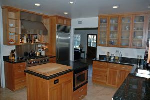 Modern kitchen with wood cabinets, stainless steel appliances, and a central island with black countertop.