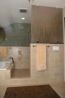 Modern bathroom with tiled shower, beige walls, wood cabinet, and hanging towels