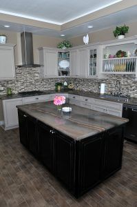 Modern kitchen with dark island, white cabinets, gray backsplash, and stainless steel appliances